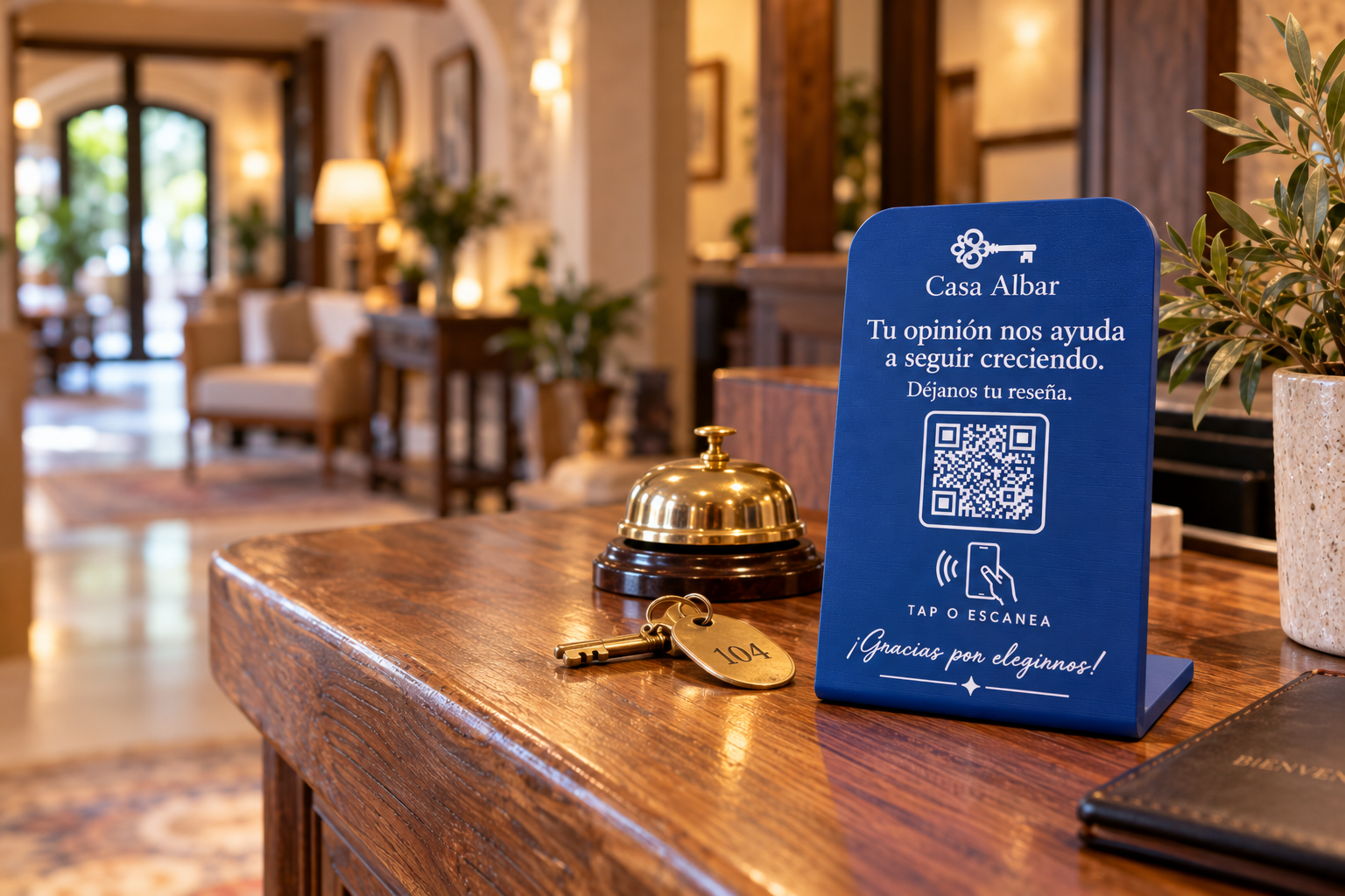 Placa NFC de reseñas azul cobalto en el mostrador de recepción de un hotel, junto a una campanilla y una llave